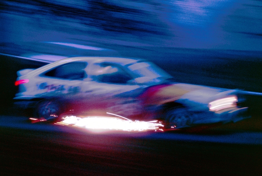 Rally car at night, sparking as it lands at the bottom of a hill.